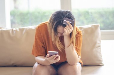 Stresli kadın, dolandırıcı online işlemden para çalıyor, kredi kartı ve cep telefonu tutuyor.