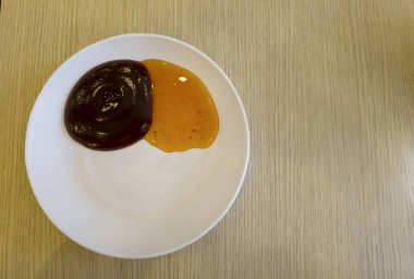 Ahşap bir arka planda beyaz bir tabakta domates sosu ve kırmızı biber sosu.