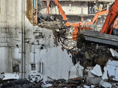 İnşaat alanında bir bina yıkmak için gerekli donanıma sahip bir kazıcı var. Görüntüyü kapat