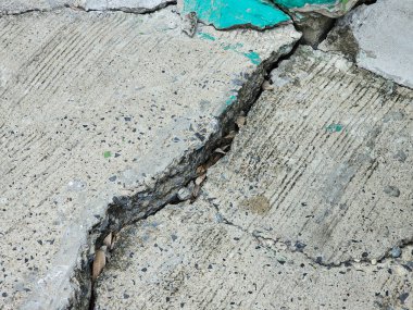 Çimento yüzeyi çökmüş ve çatlaklar oluşmuş. Bu da yolun ya da yürüme yolunun bozulduğunu gösteriyor..