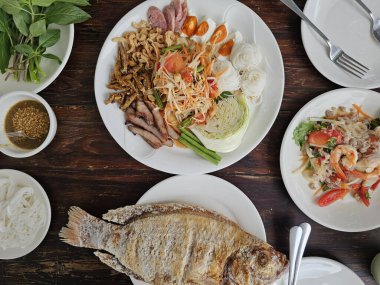 Tayland yemek masasında papaya salatası, ızgara balık, deniz ürünü cam erişte salatası var. yüksek açı görünümü