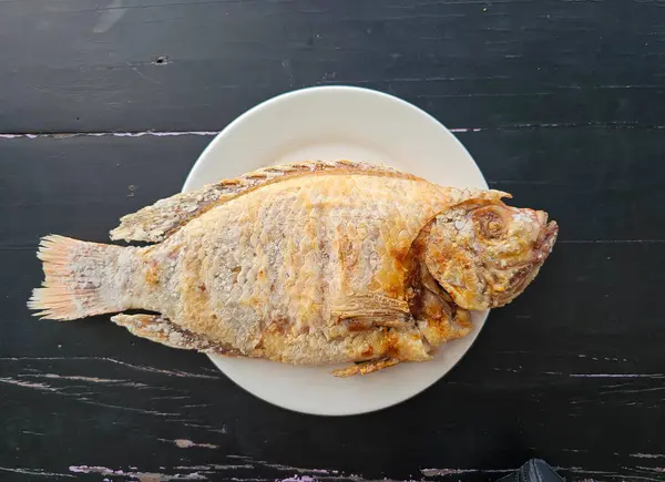 Beyaz tabakta tuzlanmış ızgara kırmızı Tilapia balığı. Masa yemeğinin üzerinde. yüksek açı görünümü