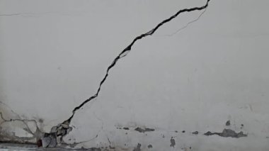Büyük çatlamış beton duvar, bir depremin neden olduğu kırık dış bariyer..