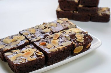 Çikolatalı tatlı, ev yapımı fırın, tabakta badem dilimli çikolatalı kek. Beyaz arka planda. yan görünüm