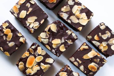 Çikolatalı Brownie parçalarını beyaz arka planda badem dilimli yap. Üst görünüm