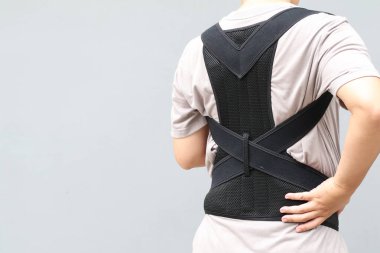 Sırt destek kemeri takan genç Asyalı adam sırt travması için bel desteği ya da bel ağrısını azaltmak için fıtık diski takıyor. kopyalama alanı olan arkaplan