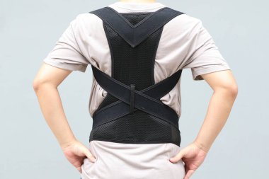 Sırt destek kemeri takan genç Asyalı adam sırt travması için bel desteği ya da bel ağrısını azaltmak için fıtık diski takıyor. arkaplan