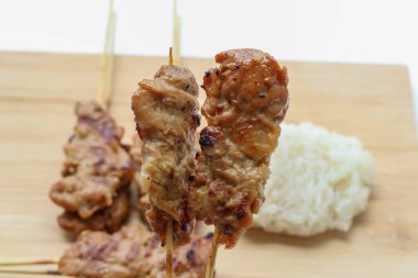 İki ızgara domuz şişi tutan bir el, popüler bir Tayland sokak yemeği, genellikle kahvaltıda yerlerdi..