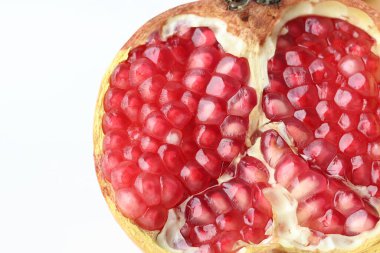 Beyaz arka planda ikiye ayrılmış nar meyvesinin yakın görüntüsü