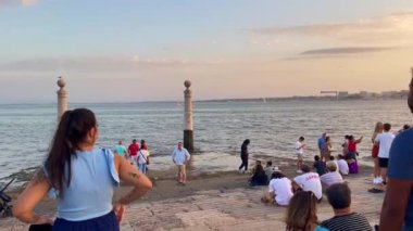 Lizbon 'daki Tagus nehrinin üzerindeki günbatımının tadını çıkaran insanlar