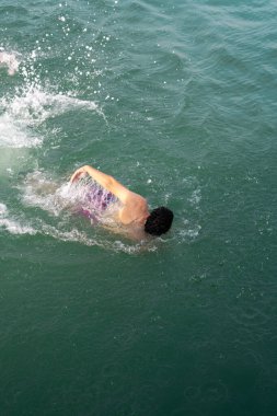 Gençler denizde yüzüyor.