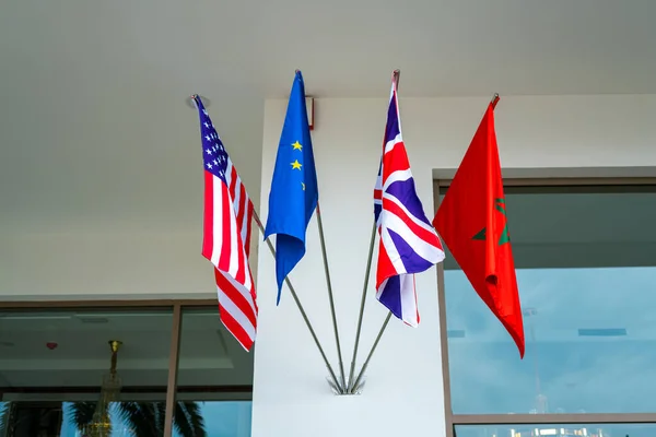 The US, EU, UK, and Moroccan flags hanging on the entrance of a luxury hotel