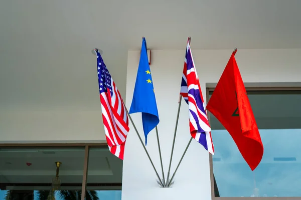 The US, EU, UK, and Moroccan flags hanging on the entrance of a luxury hotel