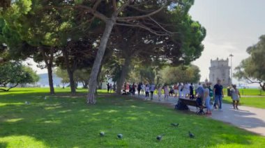 Lizbon 'da Belem kulesinin yanındaki parkta yürüyen insanlar.