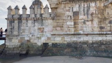 Lizbon 'daki Belem kulesinin yakınlarında yürüyen turistler