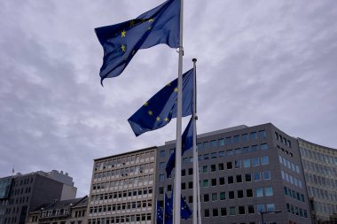 European Union flags waving outdoors with a cloudy sky in the background clipart