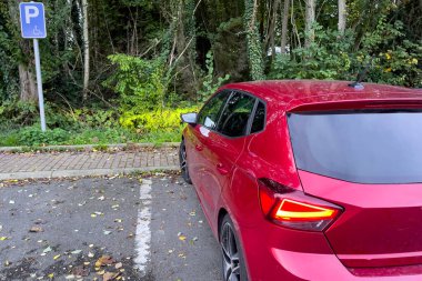 Kırmızı koltuklu İbiza arabası park yerinde park etmiş, trafik lambası açık.