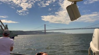 Lizbon 'da Tagus nehrinde yelken açan bir donanma gemisinden hareket eden bir feribotun görüntüsü.