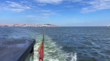 Portekiz bayrağı Lizbon, Portekiz 'deki Tagus nehrinde yelken açan bir feribotun arkasında dalgalanıyor.