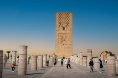 Rabat, Fas 'taki Hasan Kulesi' nin yanındaki ortaçağ sütunlarında yürüyen insanlar.