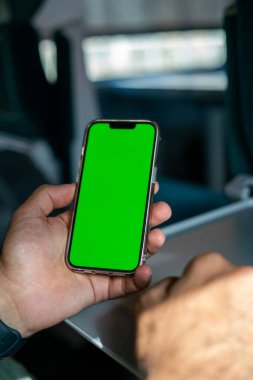 Kimliği belirsiz adam elinde yeşil ekranlı bir akıllı telefon tutuyor.