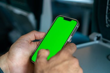 Kimliği belirsiz adam elinde yeşil ekranlı bir akıllı telefon tutuyor.