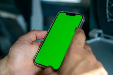 Kimliği belirsiz adam elinde yeşil ekranlı bir akıllı telefon tutuyor.
