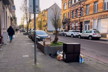Cars parked on the road side with trash piled on the street in Brussels, Belgium