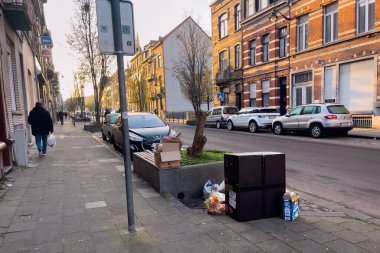 Cars parked on the road side with trash piled on the street in Brussels, Belgium