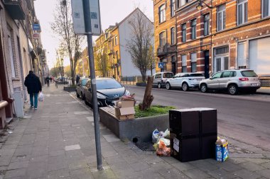 Cars parked on the road side with trash piled on the street in Brussels, Belgium