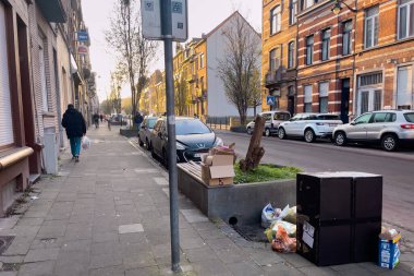 Cars parked on the road side with trash piled on the street in Brussels, Belgium