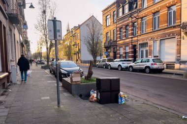 Cars parked on the road side with trash piled on the street in Brussels, Belgium