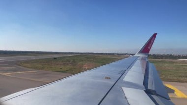 Window view of an Air Arabia commercial airplane taking off a runway at Fes Sais international airport in Morocco