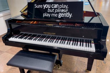 Black piano with a chair inside Brussels Zaventem international airport in Belgium 