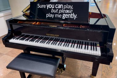 Black piano with a chair inside Brussels Zaventem international airport in Belgium 