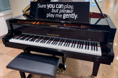 Black piano with a chair inside Brussels Zaventem international airport in Belgium 
