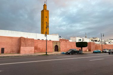 Cars driving on the road with a mosque minaret in the background in Rabat, Morocco