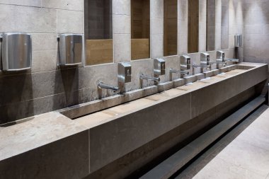 Row of automated silver taps inside a modern public bathroom