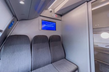 Belçika 'nın arka planında mavi ekran monitörü olan modern bir tren vagonunda boş boş koltuklar.