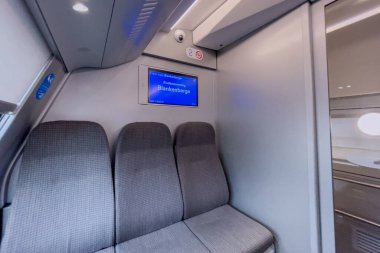 Belçika 'nın arka planında mavi ekran monitörü olan modern bir tren vagonunda boş boş koltuklar.