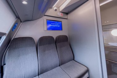 Belçika 'nın arka planında mavi ekran monitörü olan modern bir tren vagonunda boş boş koltuklar.