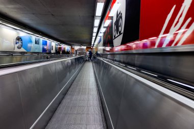 Brüksel, Belçika 'daki bir metro istasyonunun içinde hareket halindeki yatay geçitten geçen yolcular