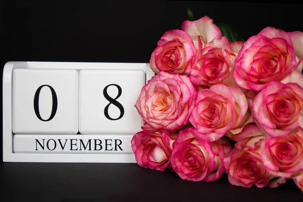11月8日木製のカレンダー 黒の背景に白 ピンクのバラが近くにあります コピースペース付きのポストカード お祝い 招待状 パーティー プロモーションの概念 — ストック写真