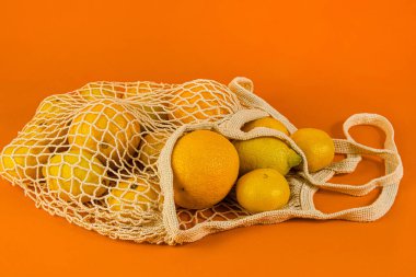 Turuncu meyve, limon, mandalina pamuk torbası, turuncu arka planda ip torbası. Ürün, ekoloji, gıda, vitaminler, alışveriş, bayrak, düzen, kopyalama alanı, sağlıklı beslenme,