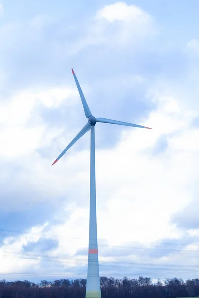 A windmill stands in a field, against the sky. Eco power plant. Concept energy, ecology, environment, light, countryside, technology, turbine, industry, europe, electricity, wind,generator,nature,eco.