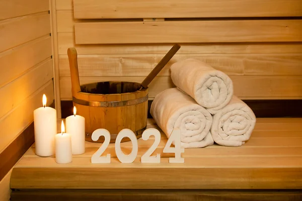 New Year card. Sauna numbers 2024 wooden white, towel ,bucket and candles. The concept of relax, health,text , holiday, poster, congratulations, invitation, lifestyle, spa, relax, mock up , copy space