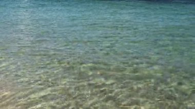 Yumuşak dalgalı turkuaz deniz suyu. Güneş ışığı yüzeye yansıyarak huzurlu bir tatil atmosferi yaratır. Seyahat ve tatil temaları için ideal.