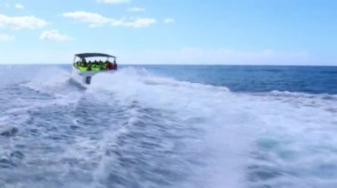 Dominik Cumhuriyeti, Punta Cana 2023. Sürat teknesi, bir grup turisti berrak mavi sularda gezintiye çıkarıyor. Tekne hızla hareket ettikçe su sıçratıyor..