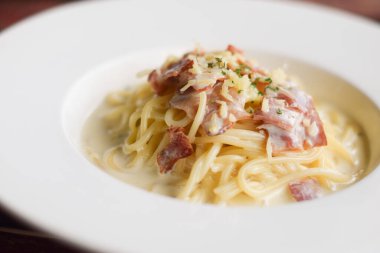 Tahta masadaki beyaz tabakta spagetti.