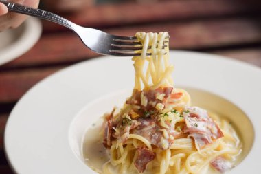 Tahta masadaki beyaz tabakta spagetti.